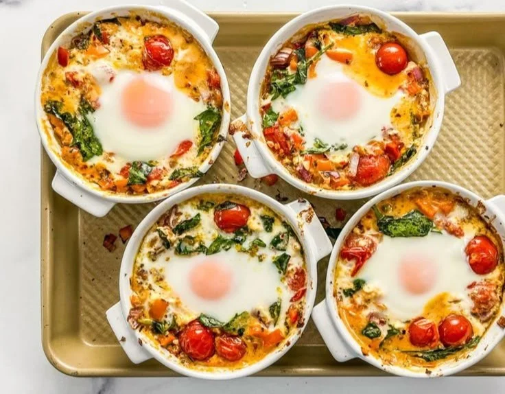 Baked feta eggs with tomatoes and spinach served in a bowl