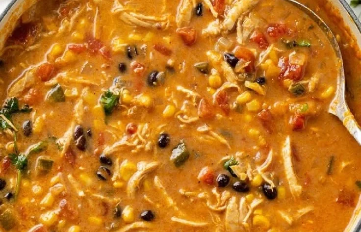 Bowl of creamy chicken tortilla soup garnished with tortilla strips and herbs