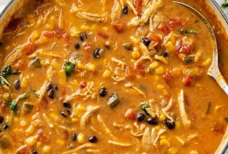 Bowl of creamy chicken tortilla soup garnished with tortilla strips and herbs