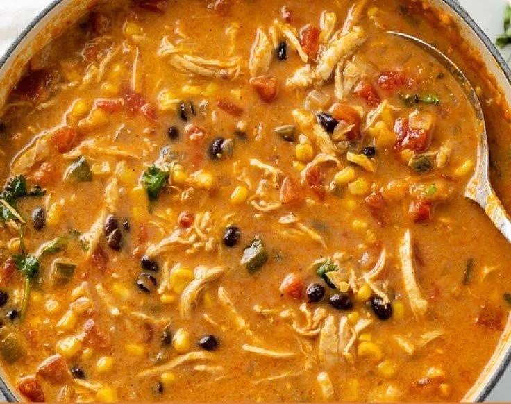 Bowl of creamy chicken tortilla soup garnished with tortilla strips and herbs