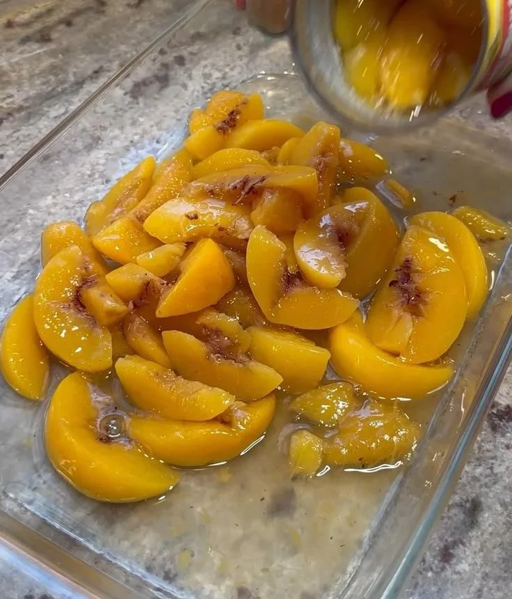 Delicious Peach Cobbler Dump Cake topped with fresh peaches and a crispy crust