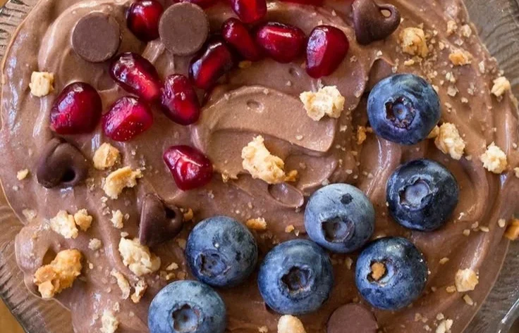 A bowl of fluffy protein fluff topped with berries and nuts.
