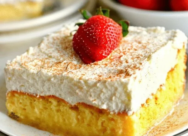 Delicious slice of gluten-free tres leches cake topped with whipped cream and strawberries