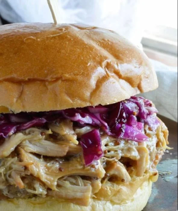 Delicious honey mustard chicken sandwich with shredded chicken and fresh ingredients.