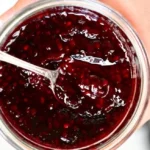 Homemade blackberry jam in a glass jar with fresh blackberries