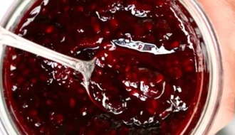 Homemade blackberry jam in a glass jar with fresh blackberries