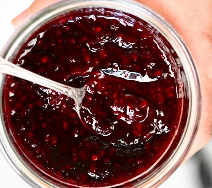 Homemade blackberry jam in a glass jar with fresh blackberries
