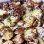 Cheesy mushroom casserole ready to serve, topped with golden cheese and herbs.