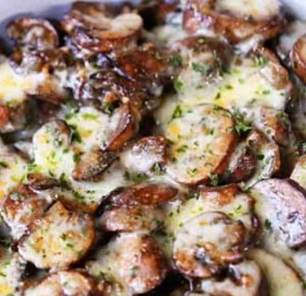 Cheesy mushroom casserole ready to serve, topped with golden cheese and herbs.