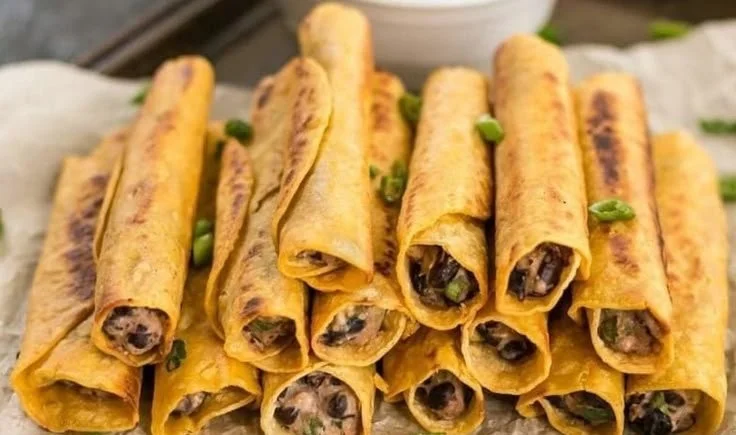Plate of creamy black bean taquitos with toppings