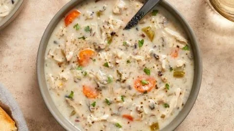 Creamy crockpot chicken wild rice soup in a bowl with fresh herbs