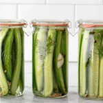 Homemade dill pickles in a jar with fresh herbs and spices