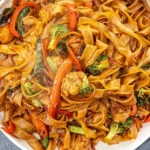 A plate of easy Drunken Noodles (Pad Kee Mao) garnished with fresh basil and lime.