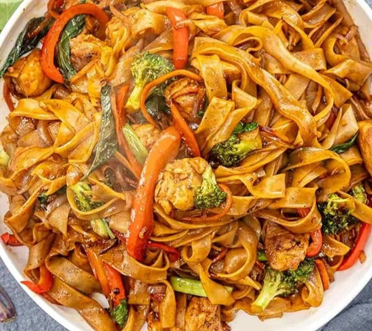A plate of easy Drunken Noodles (Pad Kee Mao) garnished with fresh basil and lime.