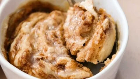 Easy gluten free cinnamon roll in a mug topped with icing