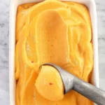 Delicious homemade peach sorbet in a bowl garnished with fresh peaches