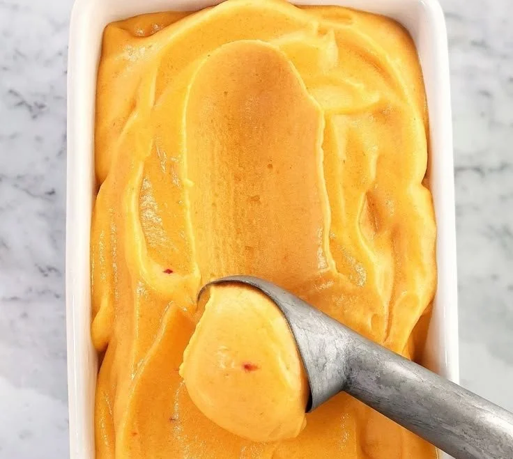 Delicious homemade peach sorbet in a bowl garnished with fresh peaches