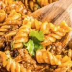 A delicious bowl of enchilada pasta topped with cheese and fresh herbs