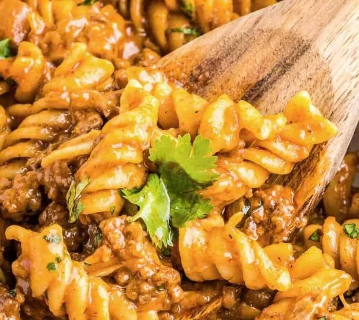 A delicious bowl of enchilada pasta topped with cheese and fresh herbs