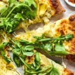 Lemon Artichoke Pizza topped with fresh arugula slice on a wooden table