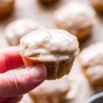 Mini chai muffins topped with vanilla bean glaze on a wooden table.