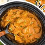 A plate of slow cooker butter chicken served with rice and naan bread.