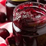 Jar of homemade cherry vanilla jam on a wooden table