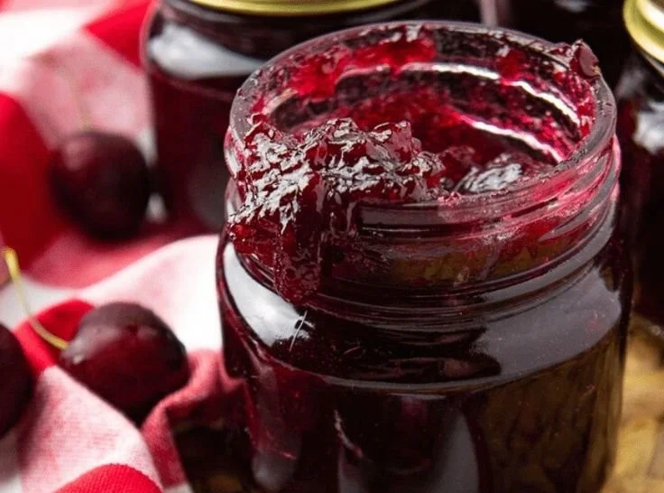 Jar of homemade cherry vanilla jam on a wooden table