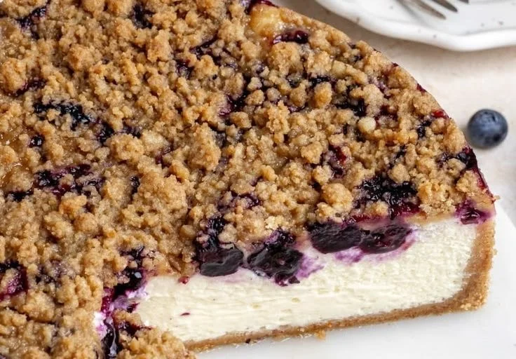 Creamy blueberry cheesecake topped with fresh blueberries and a graham cracker crust.