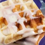 Gluten free cinnamon roll waffles topped with icing and cinnamon