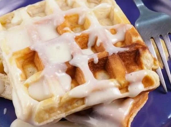 Gluten free cinnamon roll waffles topped with icing and cinnamon