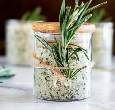 Homemade rosemary salt in a glass jar with fresh rosemary sprigs