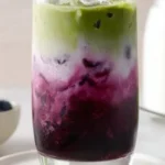 Iced blueberry matcha latte garnished with fresh blueberries