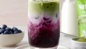 Iced blueberry matcha latte garnished with fresh blueberries