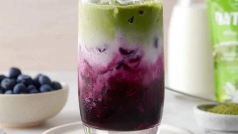 Iced blueberry matcha latte garnished with fresh blueberries