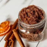 Orange Spiced Sugar Scrub in a jar with orange slices and spices around it.