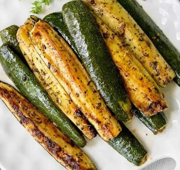 Bowl of roasted zucchini seasoned with herbs and spices.
