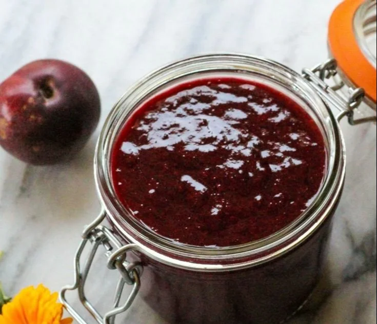 Homemade slow cooker plum butter jar on kitchen counter