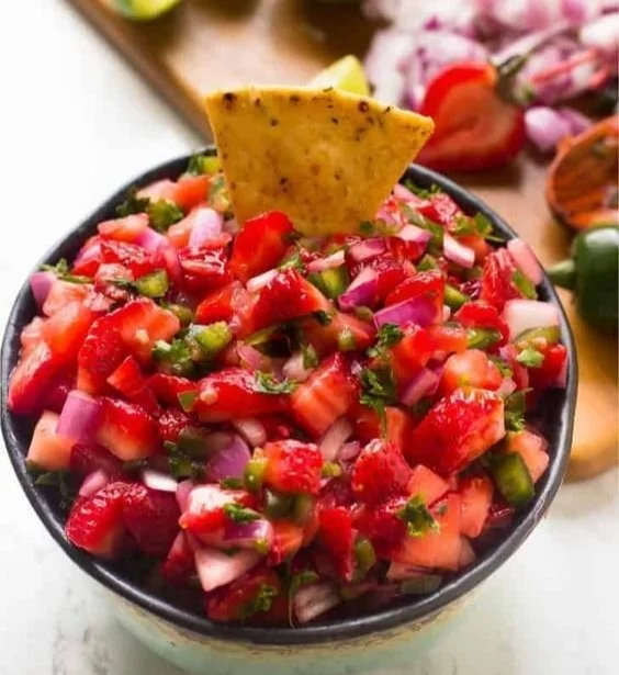 Bowl of fresh strawberry jalapeño salsa with ingredients on the side.