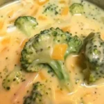 Bowl of creamy broccoli cheddar soup with fresh broccoli and cheese