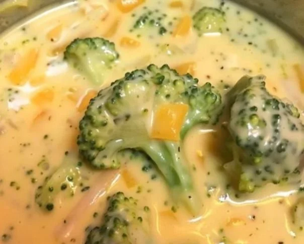 Bowl of creamy broccoli cheddar soup with fresh broccoli and cheese
