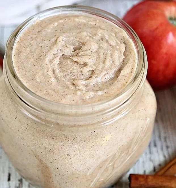 Homemade apple cinnamon sugar scrub in a glass jar with a spoon.