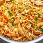 Plate of Easy Chicken Pad Thai garnished with lime and peanuts