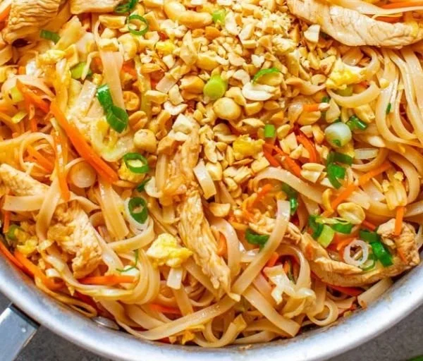 Plate of Easy Chicken Pad Thai garnished with lime and peanuts