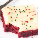 Delicious red velvet cookie bars on a plate, topped with cream cheese frosting.