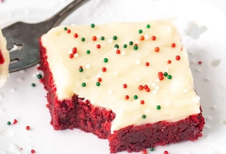 Delicious red velvet cookie bars on a plate, topped with cream cheese frosting.