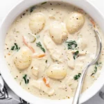 Bowl of homemade chicken gnocchi soup with vegetables and herbs.