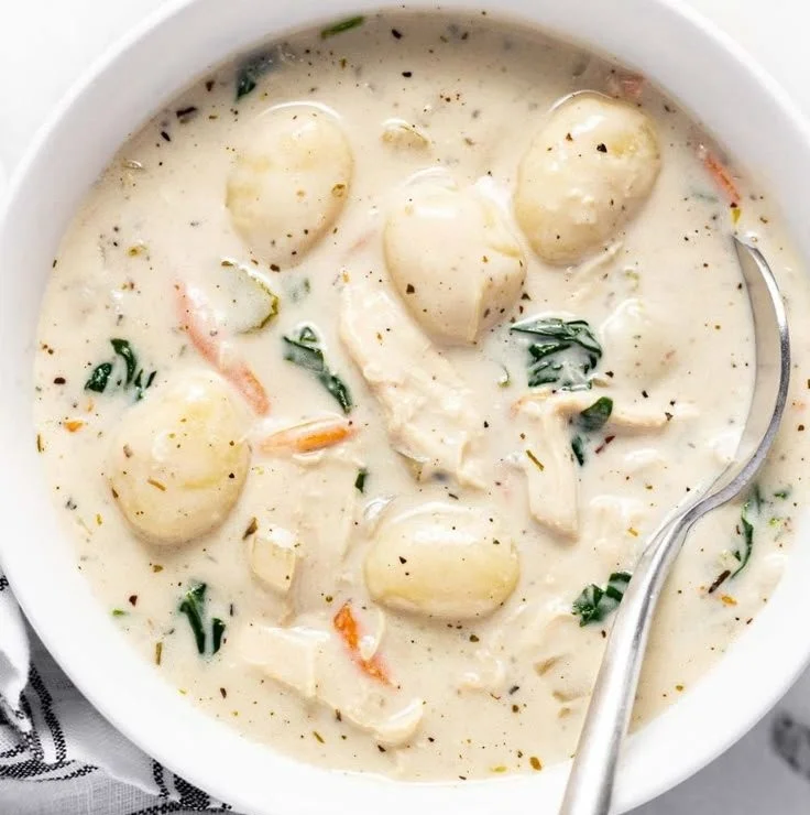Bowl of homemade chicken gnocchi soup with vegetables and herbs.