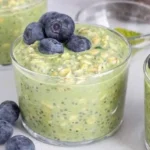 A bowl of matcha overnight oats topped with fresh fruits and nuts.