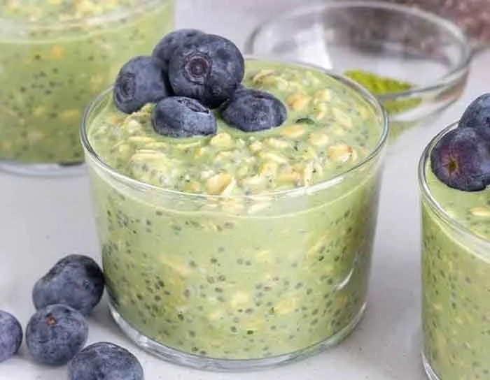 A bowl of matcha overnight oats topped with fresh fruits and nuts.